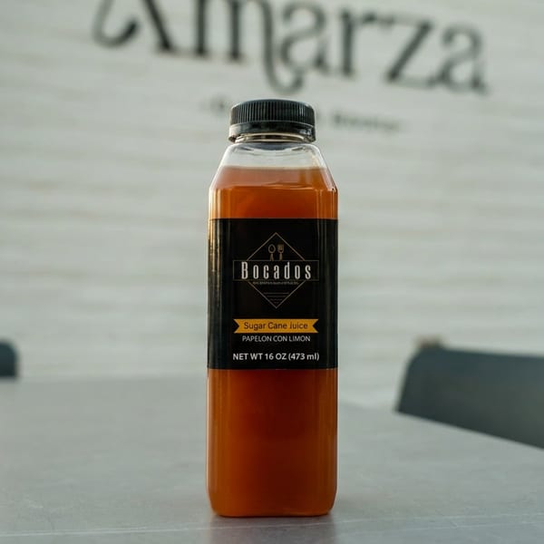 Bocados sugar cane juice bottle on a table with "Amarza" restaurant sign in the background.